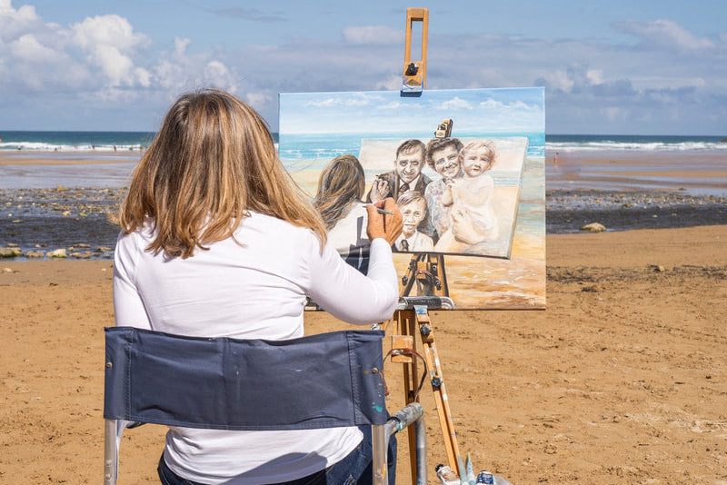 Person painting a portrait on an easel at the beach